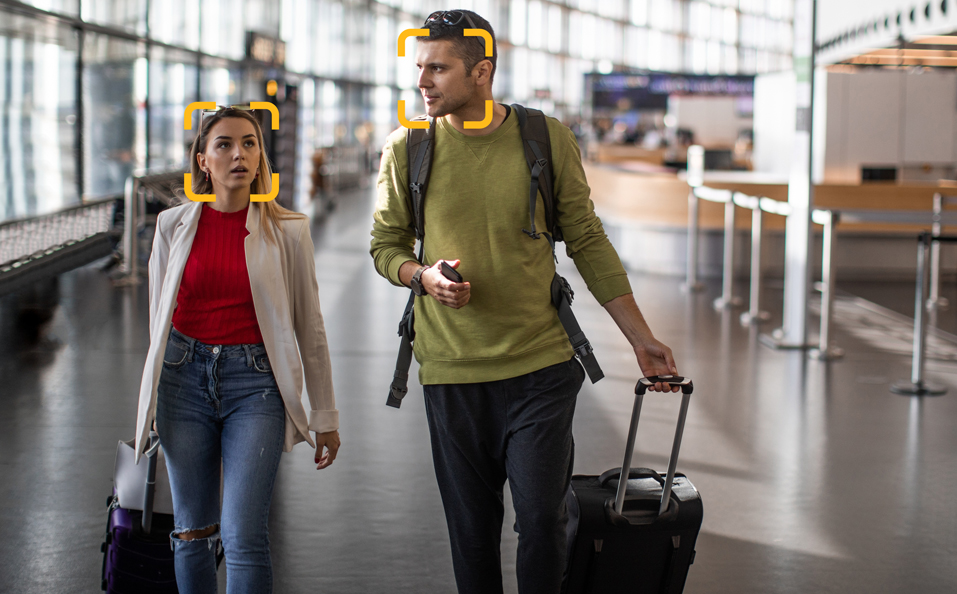 people walking through airport with facial recognition bounding boxes around faces